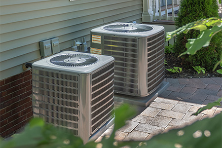 Two central air conditioning units installed outside a residential building