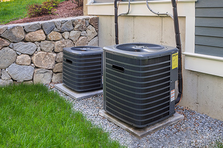 Two well-maintained outdoor air conditioning units placed on concrete slabs