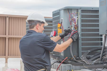 a man working on an outdoor HVAC unit